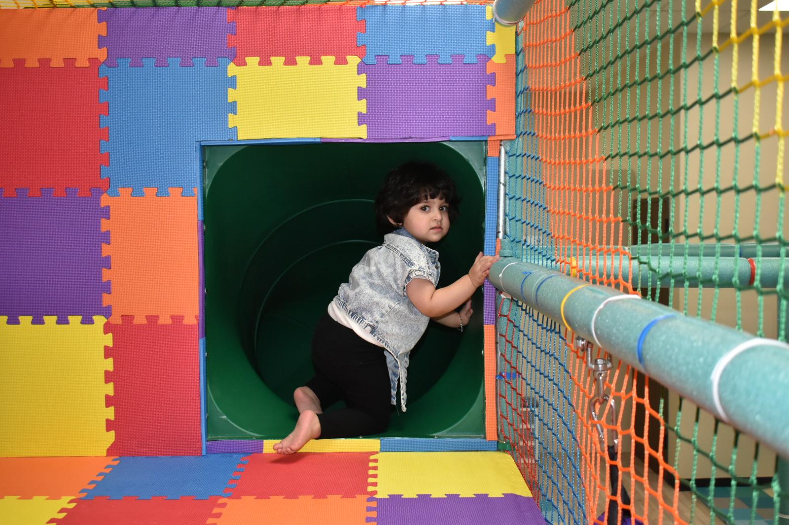 Young boy seated in the kiddiekingdomtx' birthday party room, beaming with joy as he celebrates his second birthday surrounded by friends.